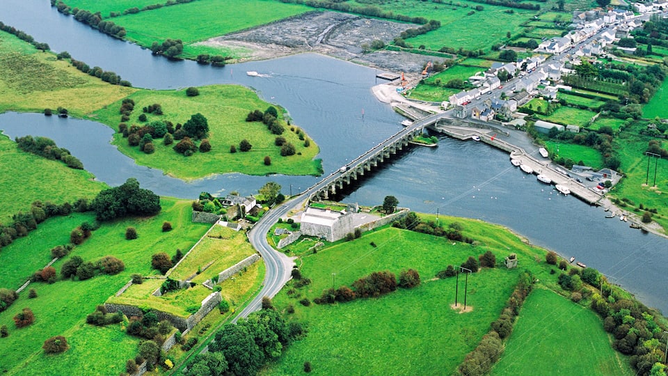 A river with a bridge, green fields, and a small town.