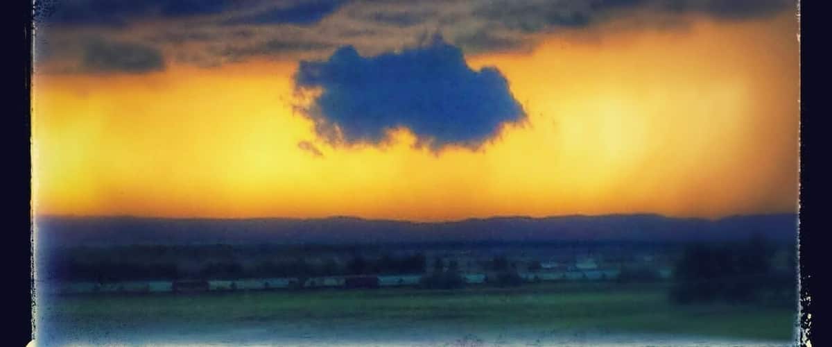 A sunset over a rural landscape with a prominent cloud formation.