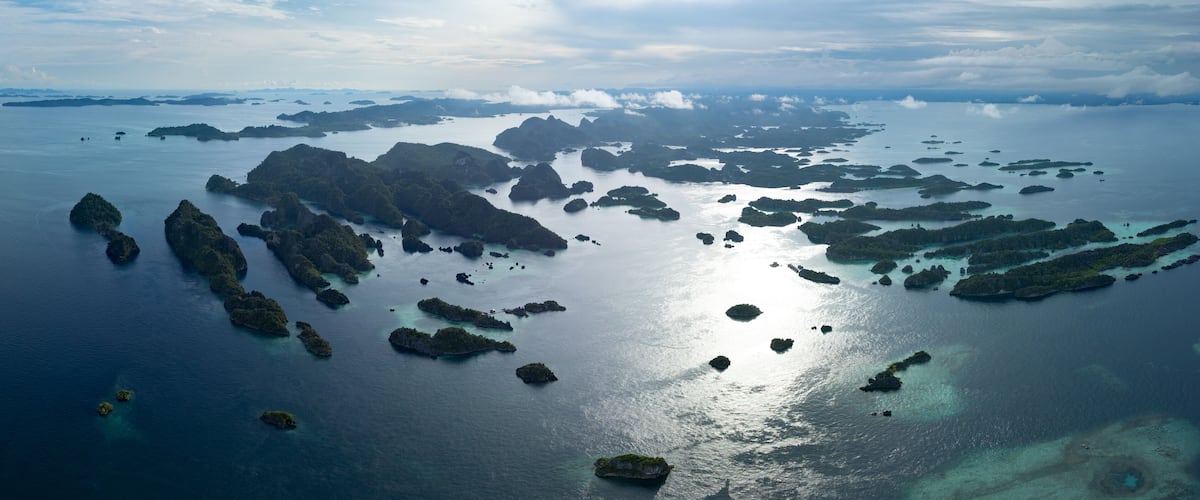 An aerial view of a chain of islands with clear turquoise waters and lush greenery.
