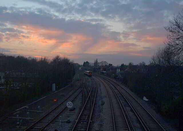 Sunset from Brokenford Lane footbridge. Looking down the railway line towards the sunset from 1769848, as a service approaches Totton station. If you can make the out, the houses on the right front onto Ringwood Road.