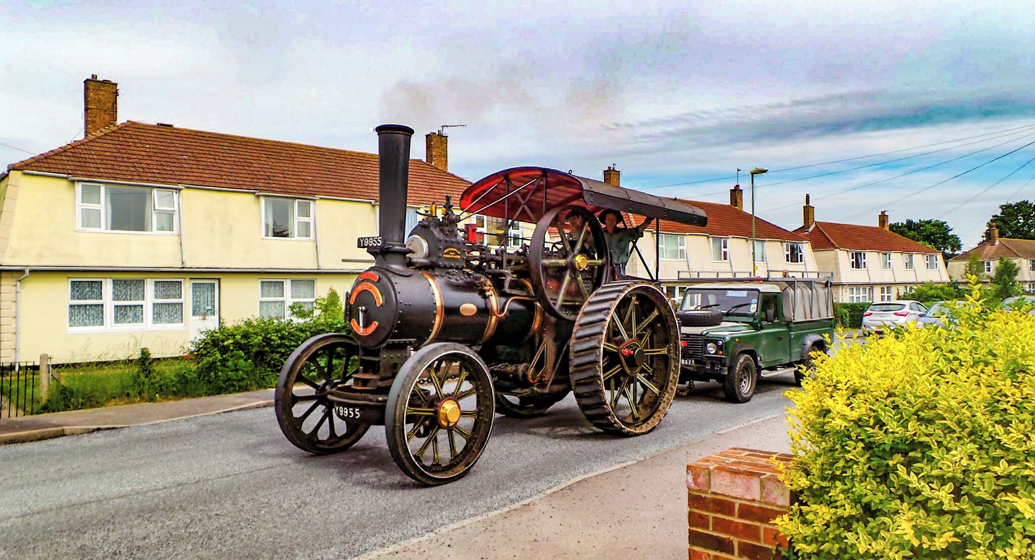 A steam locomotive with large wheels parked on a residential street.