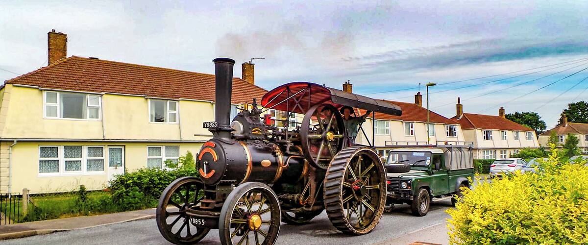 A steam locomotive with large wheels parked on a residential street.