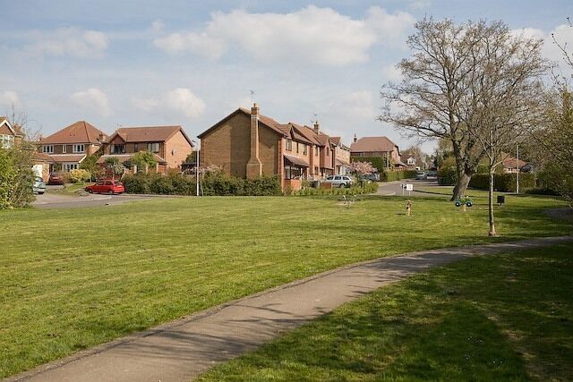 A suburban neighborhood with houses, a grassy lawn, and a tree.