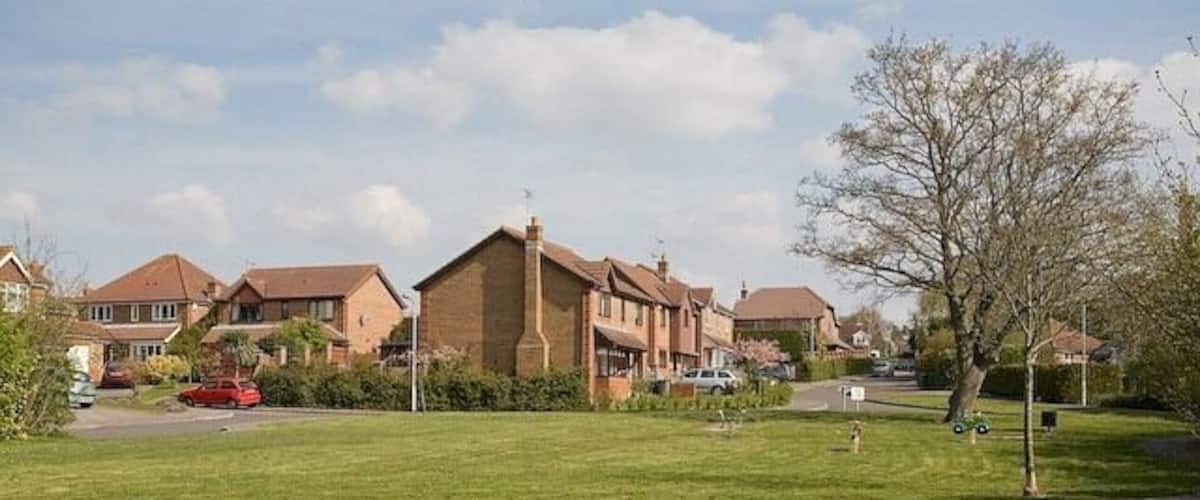 A suburban neighborhood with houses, a grassy lawn, and a tree.