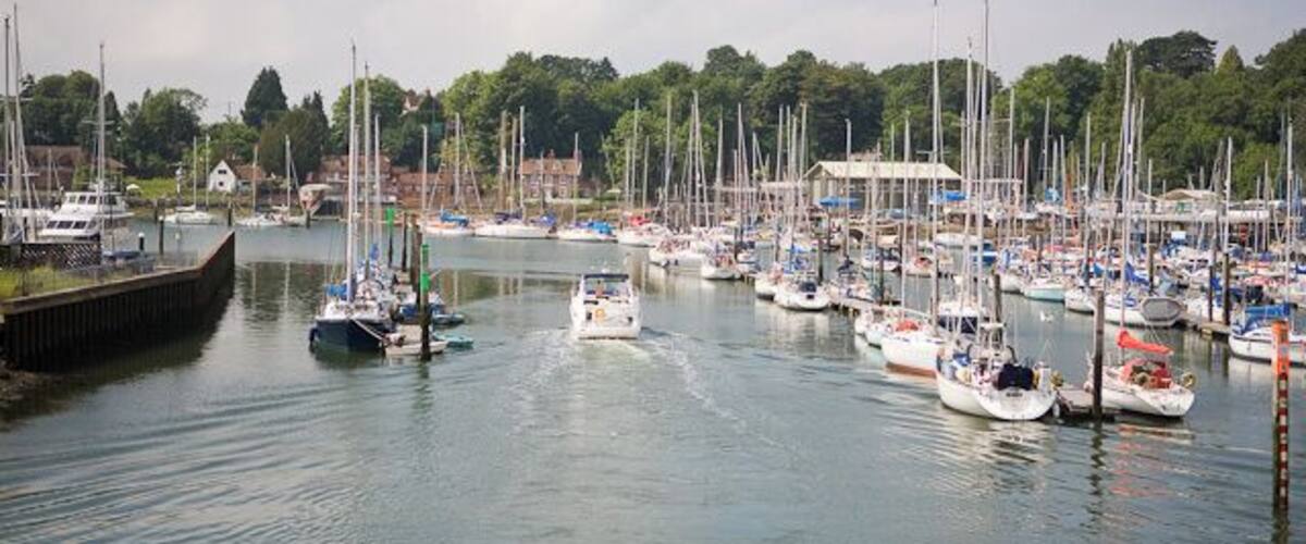 A marina with numerous sailboats docked along the waterfront.