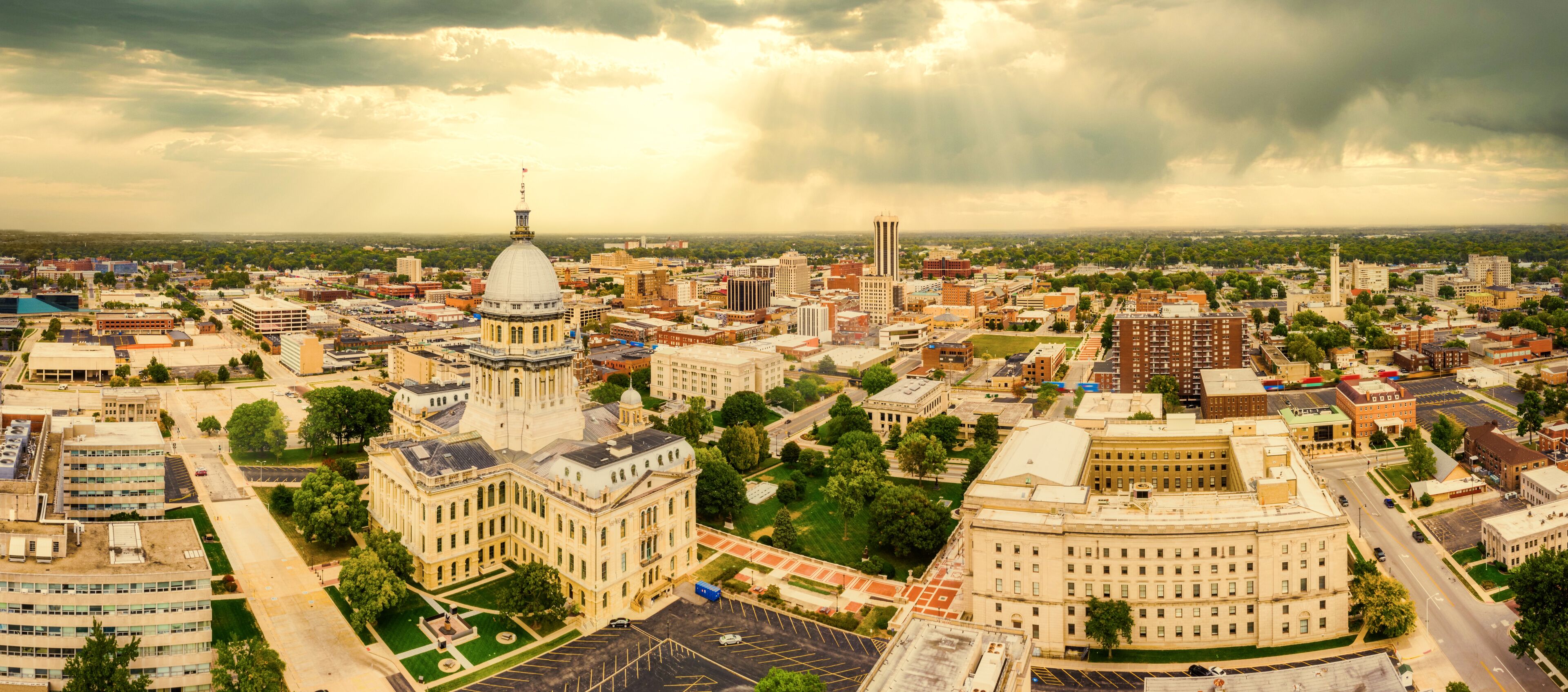 A cityscape with a prominent historical building with a dome, surrounded by modern buildings and a cloudy sky.