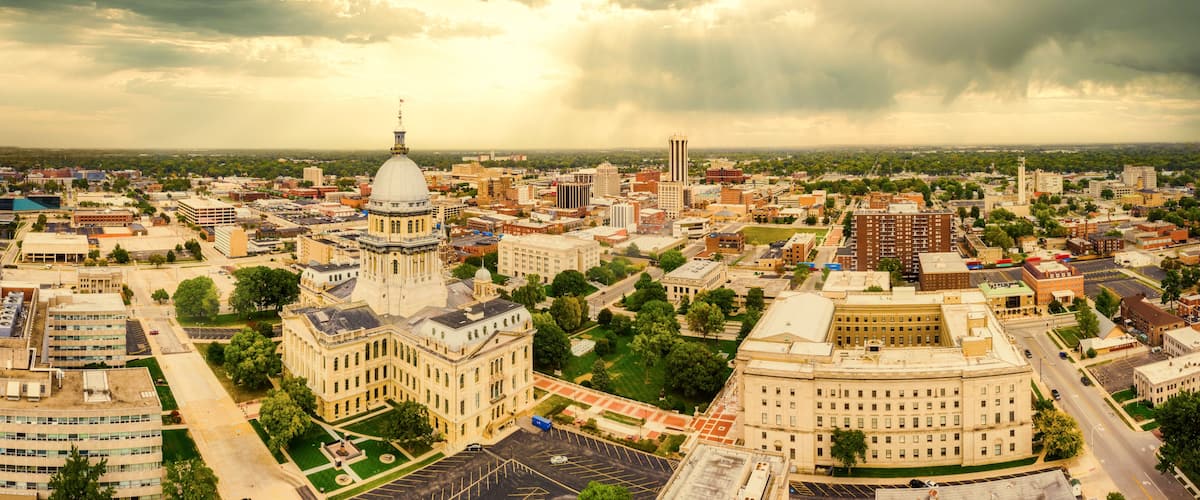 A cityscape with a prominent historical building with a dome, surrounded by modern buildings and a cloudy sky.