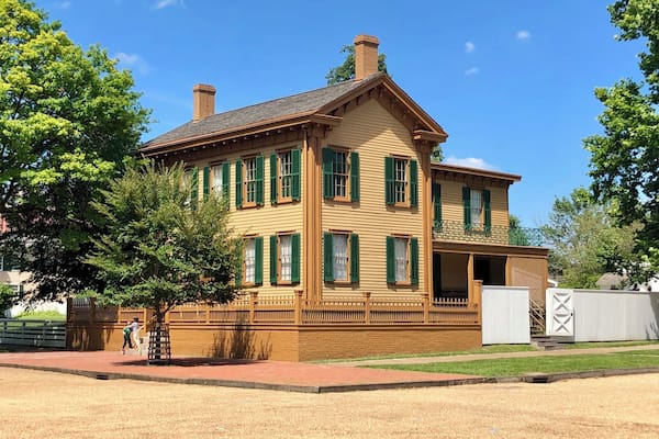 A large, two-story house with green shutters and a brick chimney.
