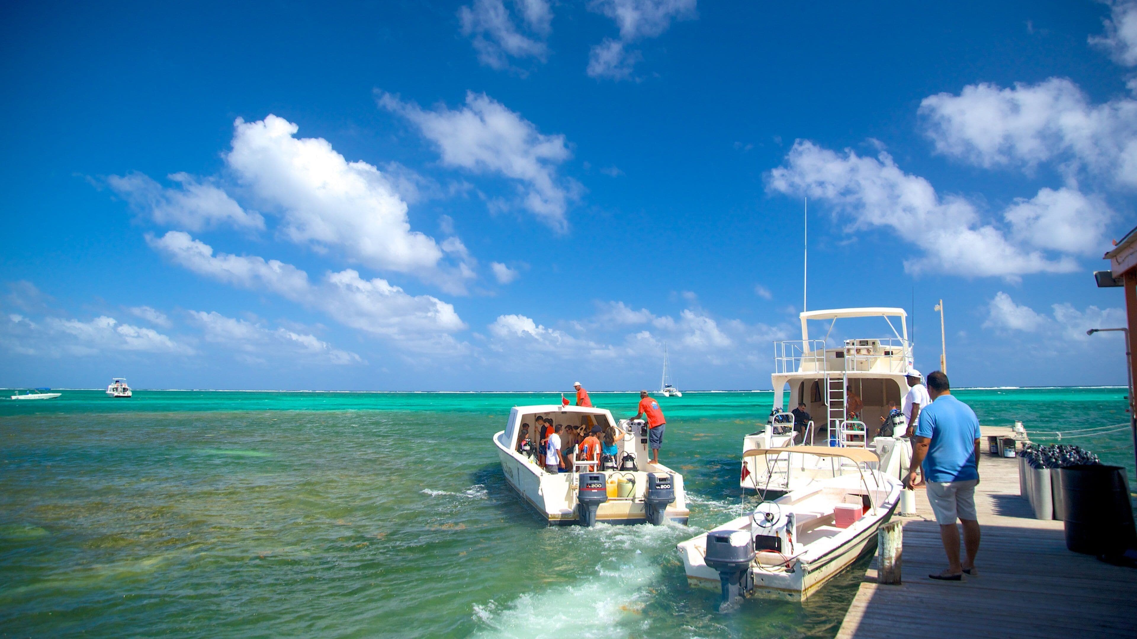 A boat docked at a pier with clear turquoise water and a bright blue sky.