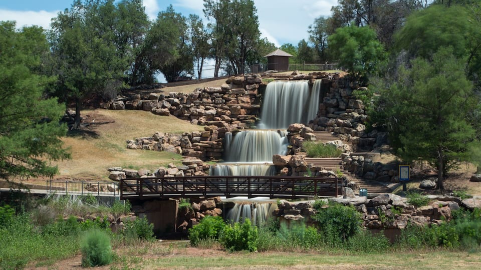 A multi-tiered waterfall, a wooden bridge, and a stone structure.