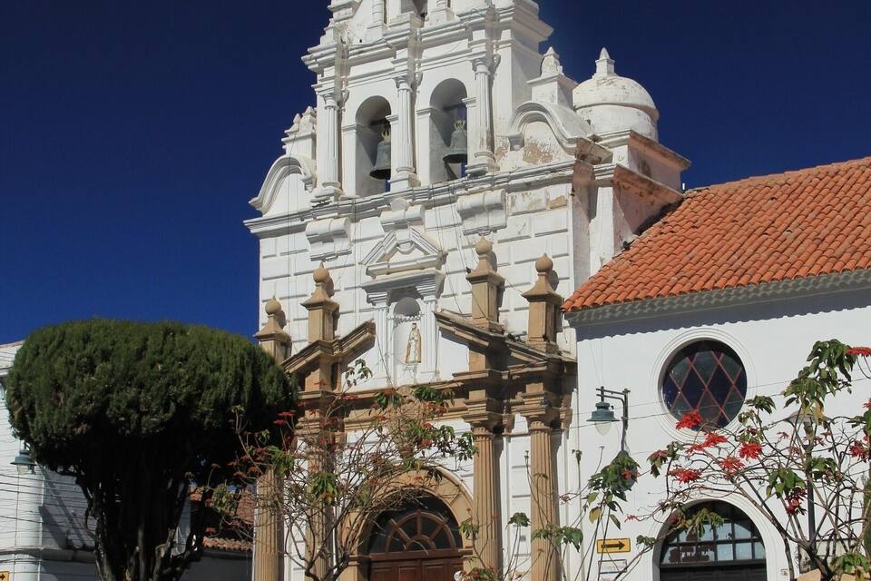 A white church with a bell tower and a red-tiled roof.