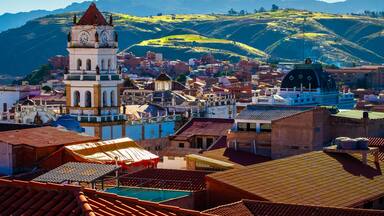 Uma cidade com uma torre do relógio imponente, um edifício em formato de cúpula e colinas ondulantes ao fundo.