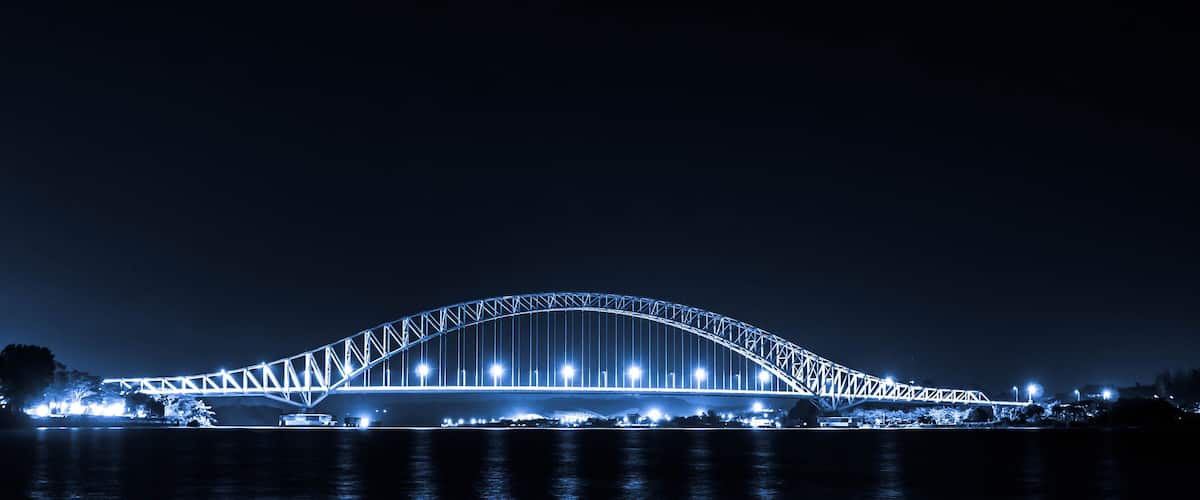 A large illuminated bridge spanning a body of water at night.