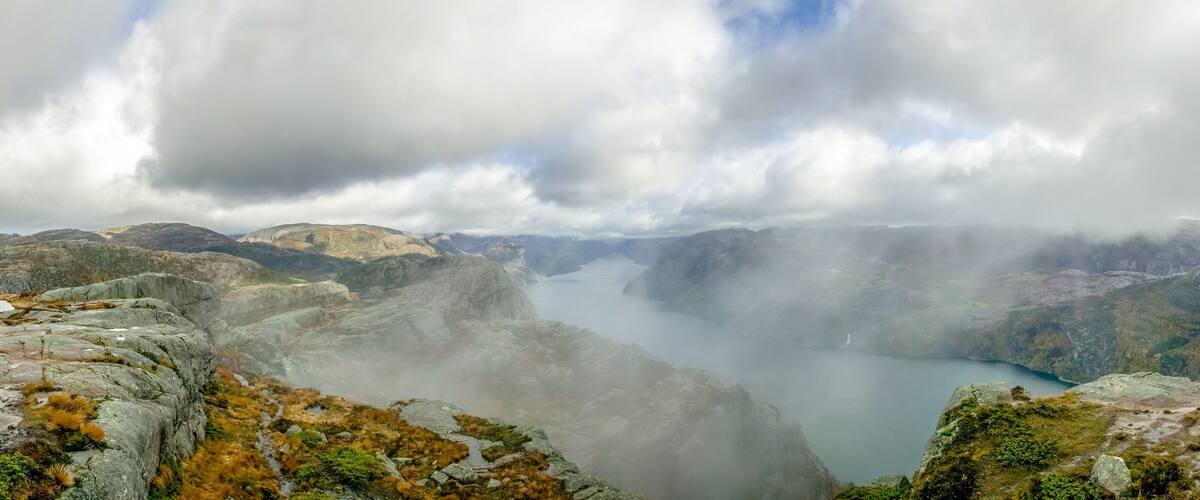 A mountainous landscape with a lake surrounded by rocky terrain and clouds.