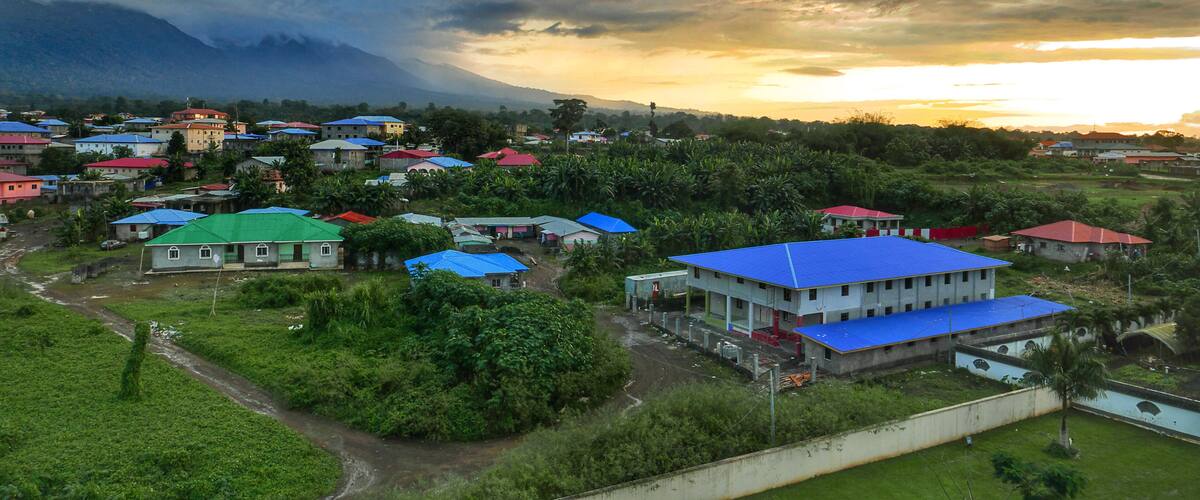 A rural village with colorful houses and a mountain in the background.
