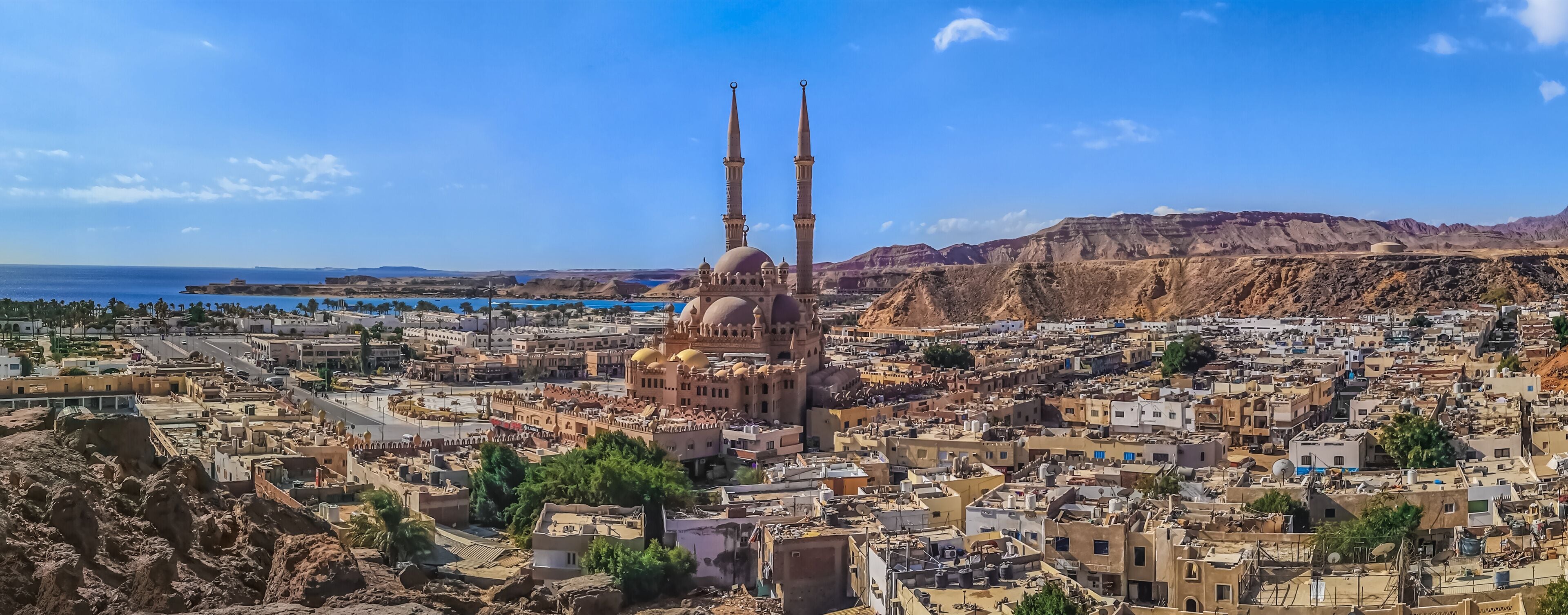 Widescreen panorama of the Old Market in Sharm El Sheikh with the Al Sahaba Mosque in the center and the Red Sea on the horizon. Aerial view of an Egyptian resort