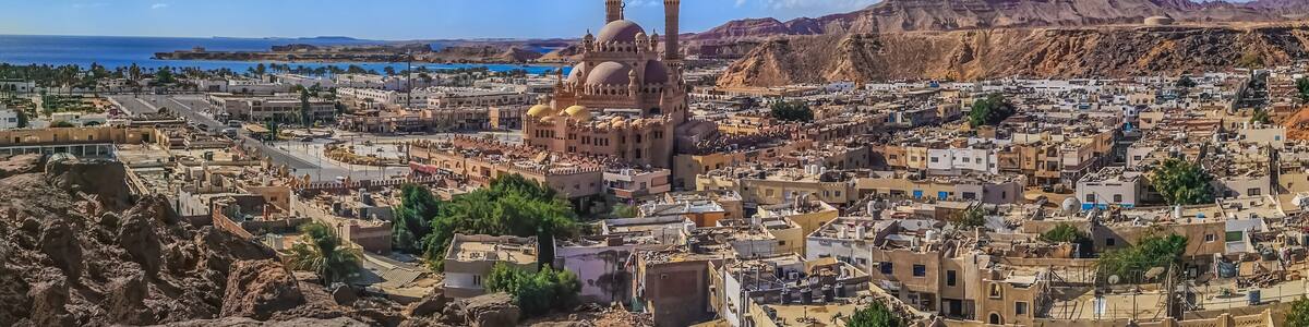 Widescreen panorama of the Old Market in Sharm El Sheikh with the Al Sahaba Mosque in the center and the Red Sea on the horizon. Aerial view of an Egyptian resort
