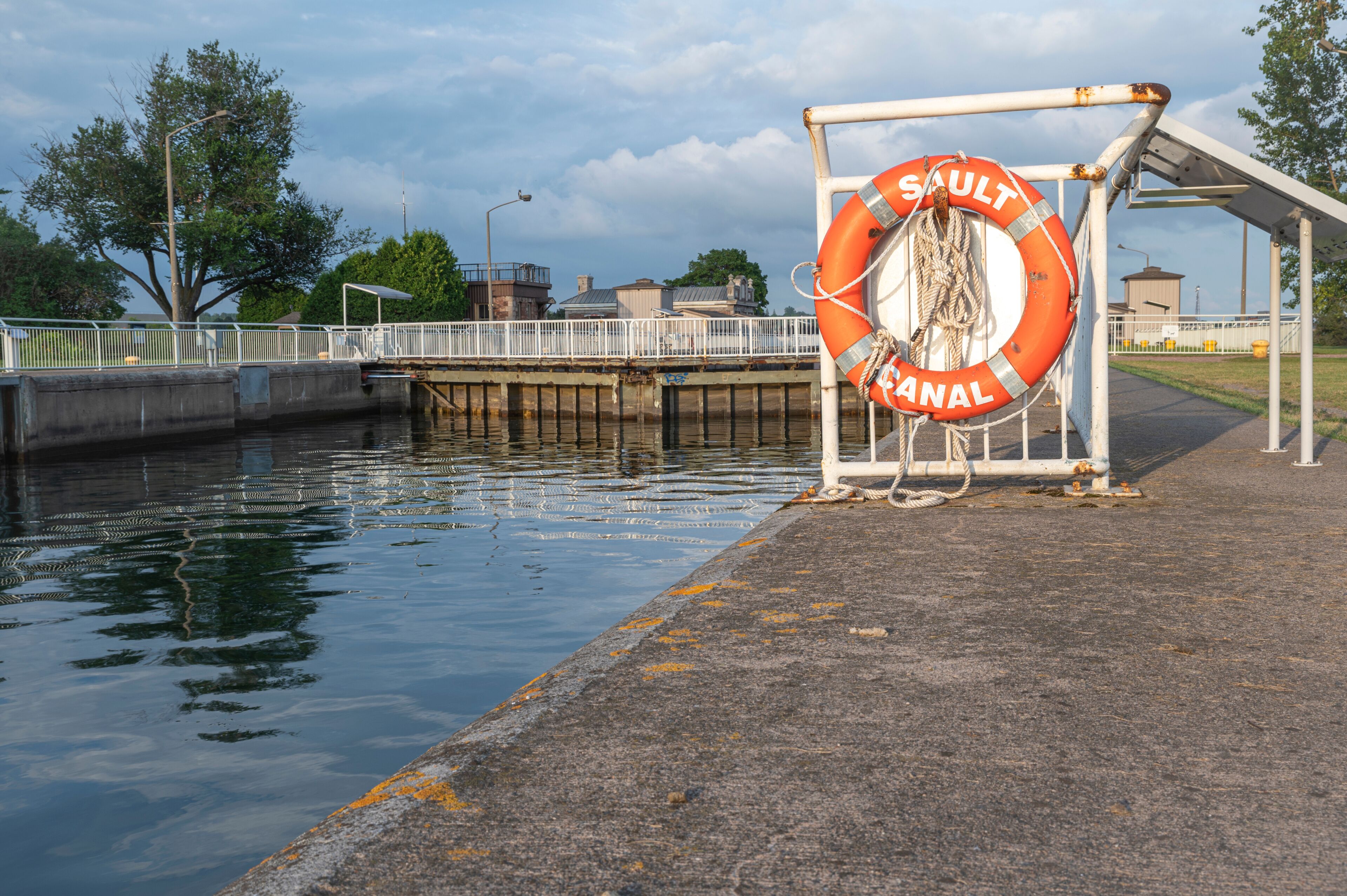 Orange Life Ring Hanging on the Waters Edge at the Sault Ste Marie Canal with a Lock in the Background