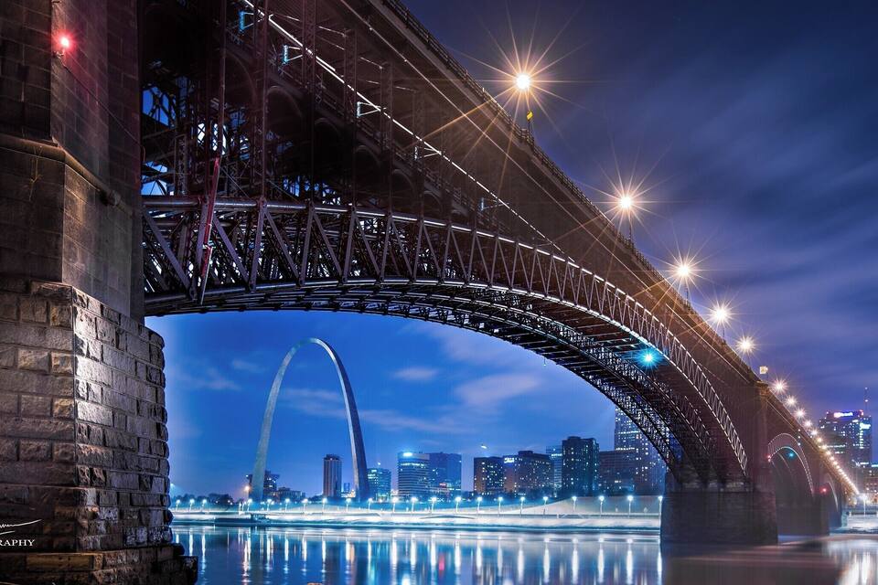 Una vista notturna di un grande ponte con le luci della città riflesse nell'acqua.