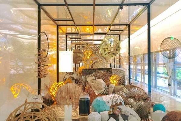A modern art installation with various sculptures and decorative items displayed in a glass enclosure.