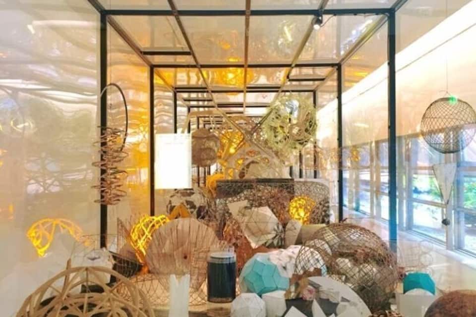 A modern art installation with various sculptures and decorative items displayed in a glass enclosure.