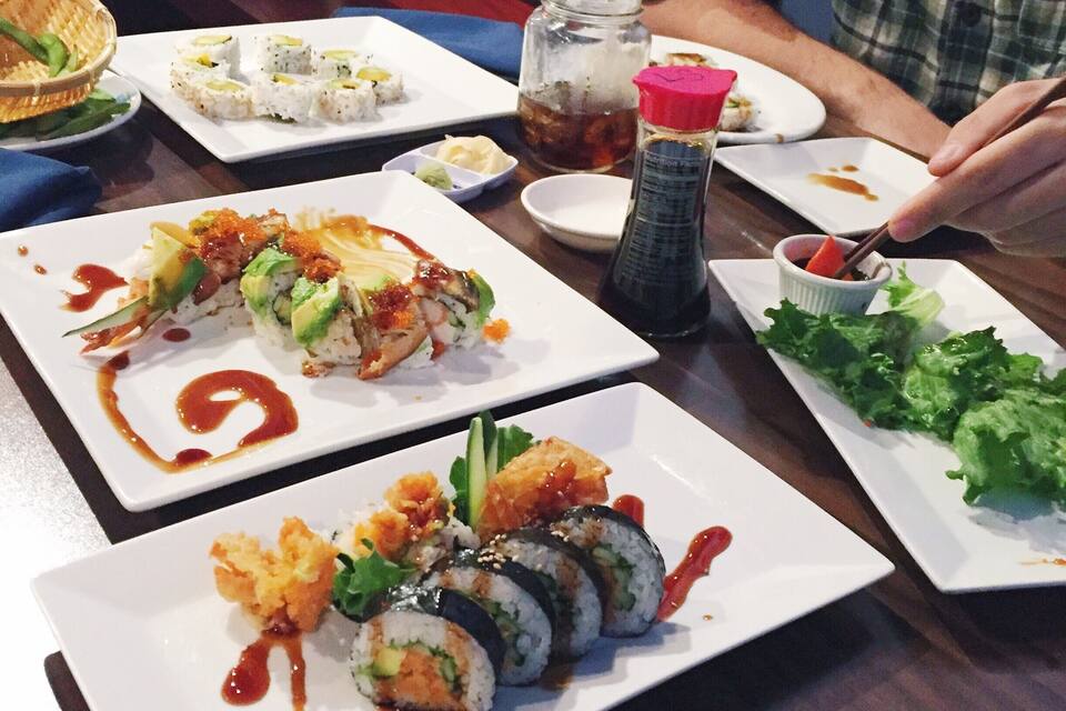 Una mesa con diversos platos de sushi, un frasco de salsa de soja y un recipiente pequeño de wasabi.
