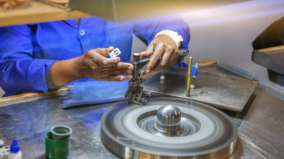 A person in a blue uniform working with a machine on a metallic surface.
