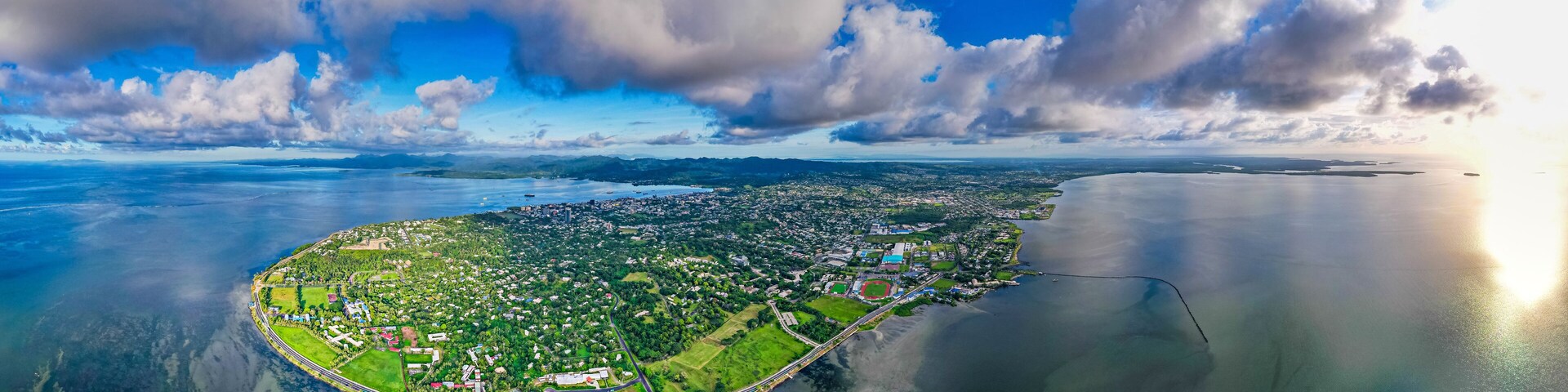 Vista aérea de uma cidade costeira com uma rodovia importante contornando uma ilha central.