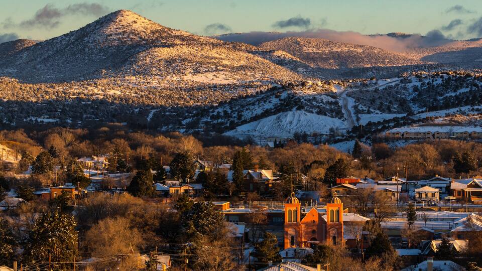 A snow-covered town with a prominent church and mountains in the background.