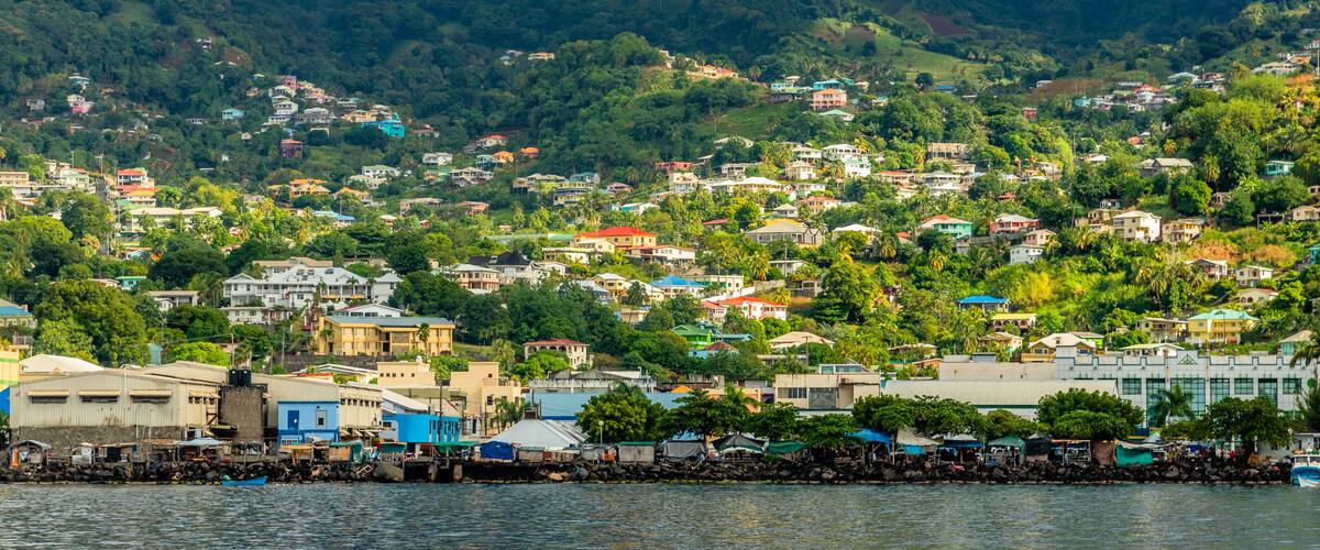 A coastal town with a mountain in the background, houses, and a body of water.