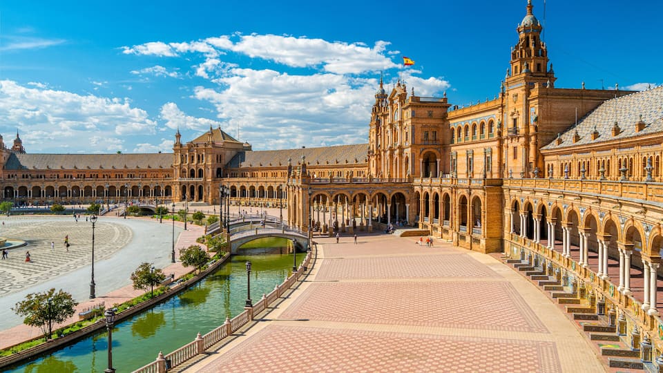 A historic building with a large courtyard, a river, and a bridge.