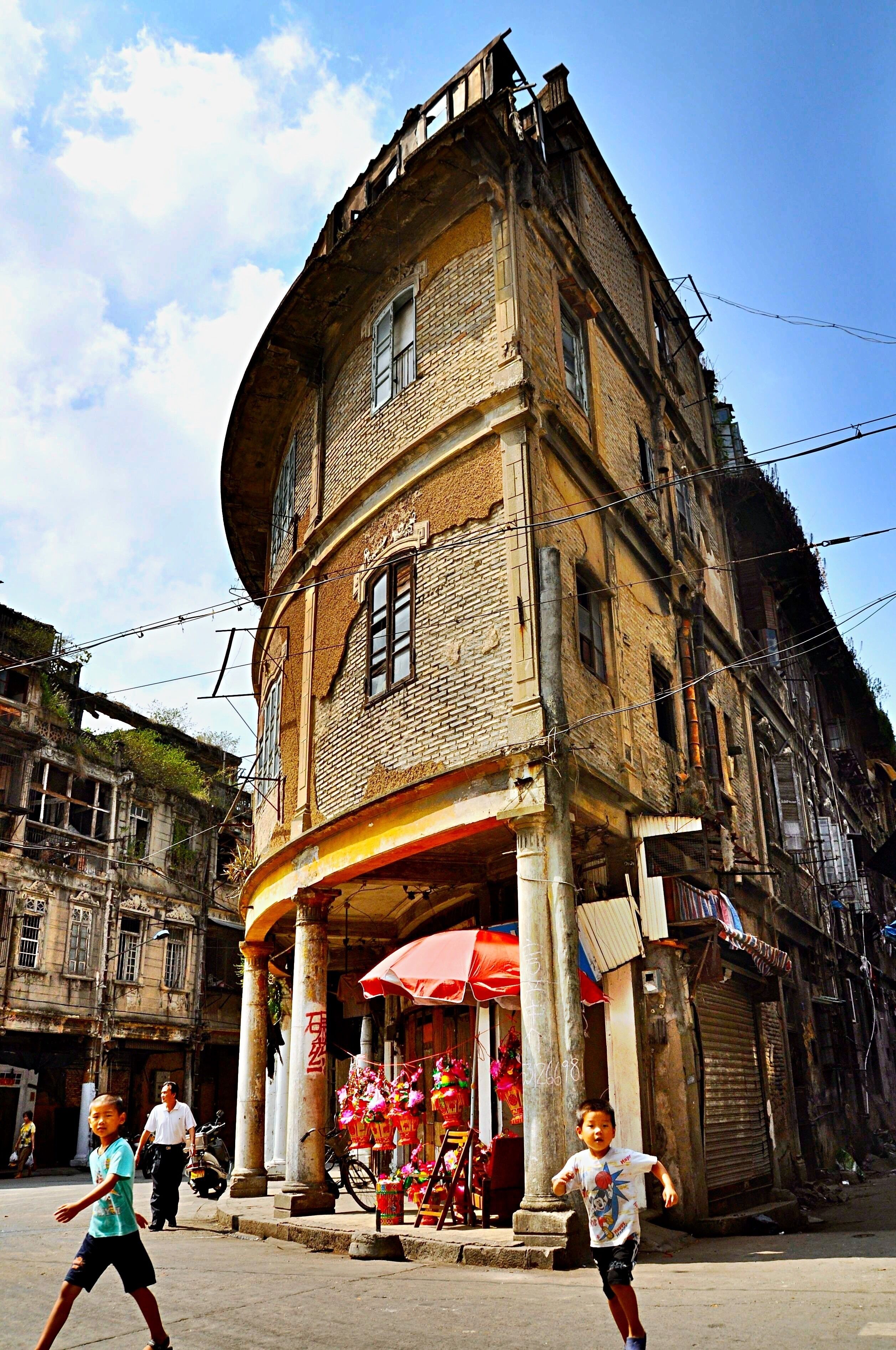 A weathered building with a curved facade, a red awning, and a bicycle parked in front.