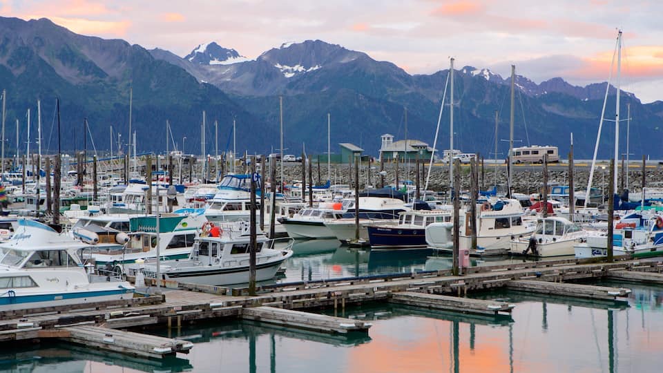 A marina with boats docked, wooden piers, and a mountainous backdrop.