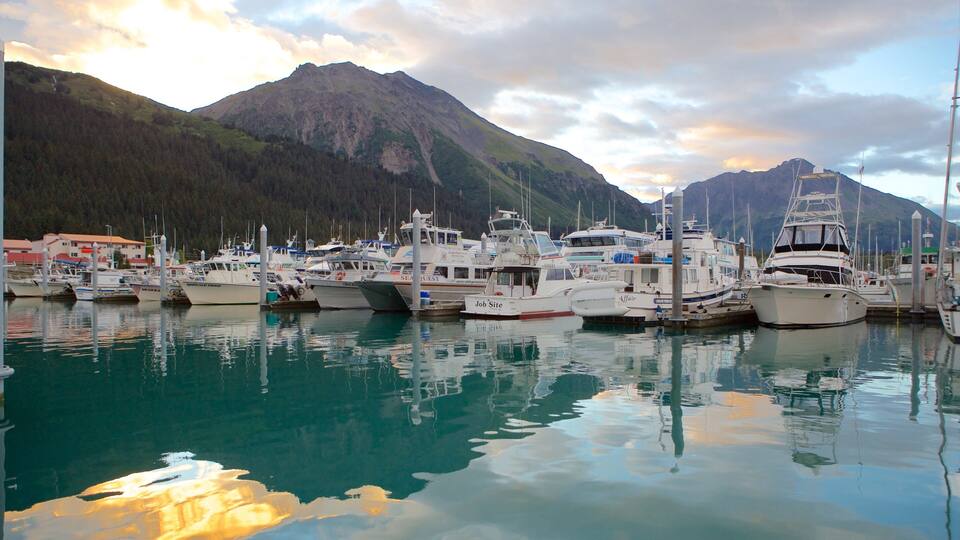 A marina with several boats docked, surrounded by mountains and a cloudy sky.