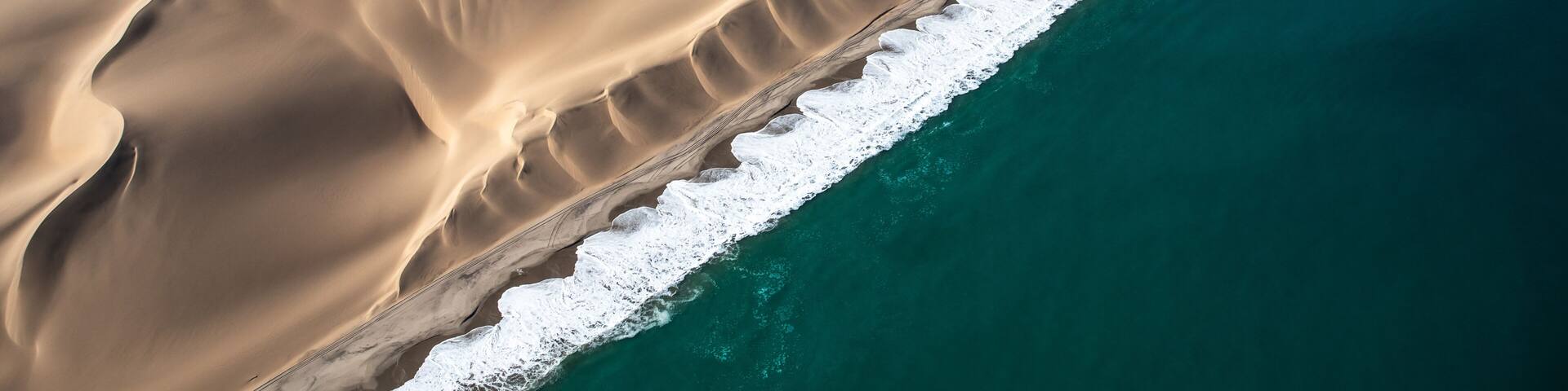 A vast desert landscape with sand dunes and a coastline.