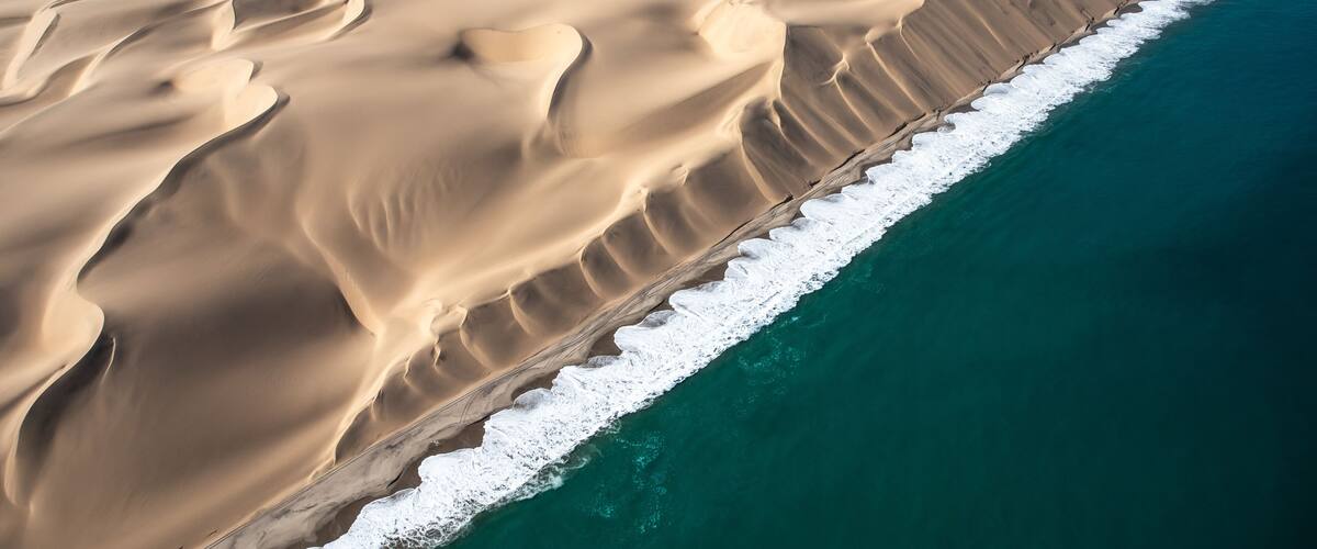 A vast desert landscape with sand dunes and a coastline.
