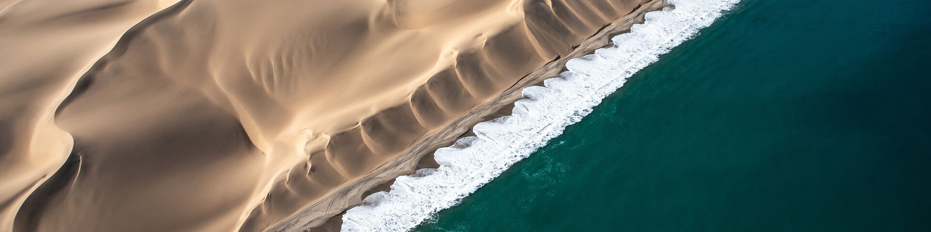 A vast desert landscape with sand dunes and a coastline.