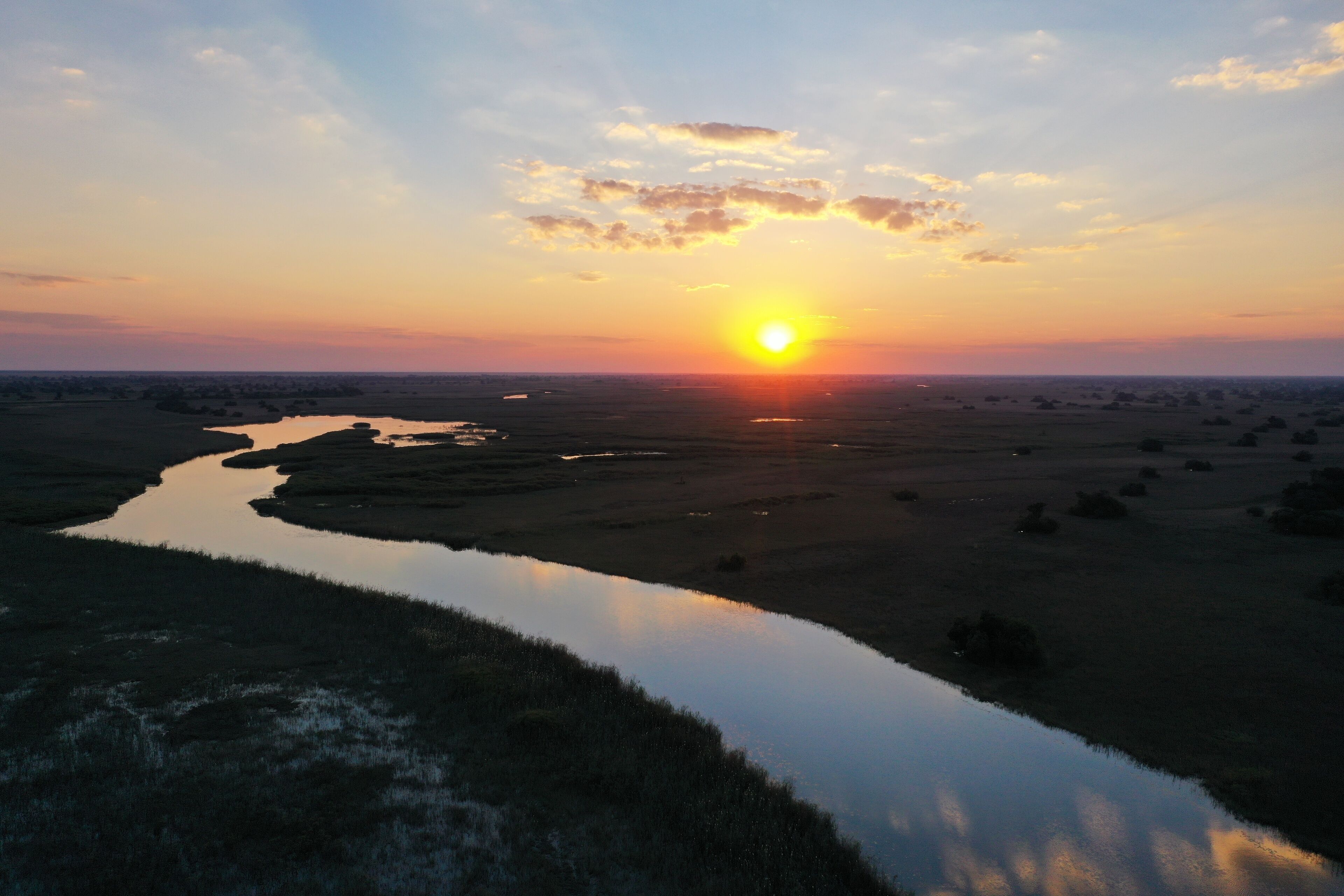 A sunset over a river with a distant city skyline.