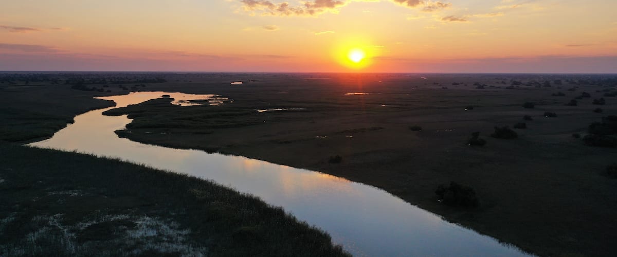 A sunset over a river with a distant city skyline.