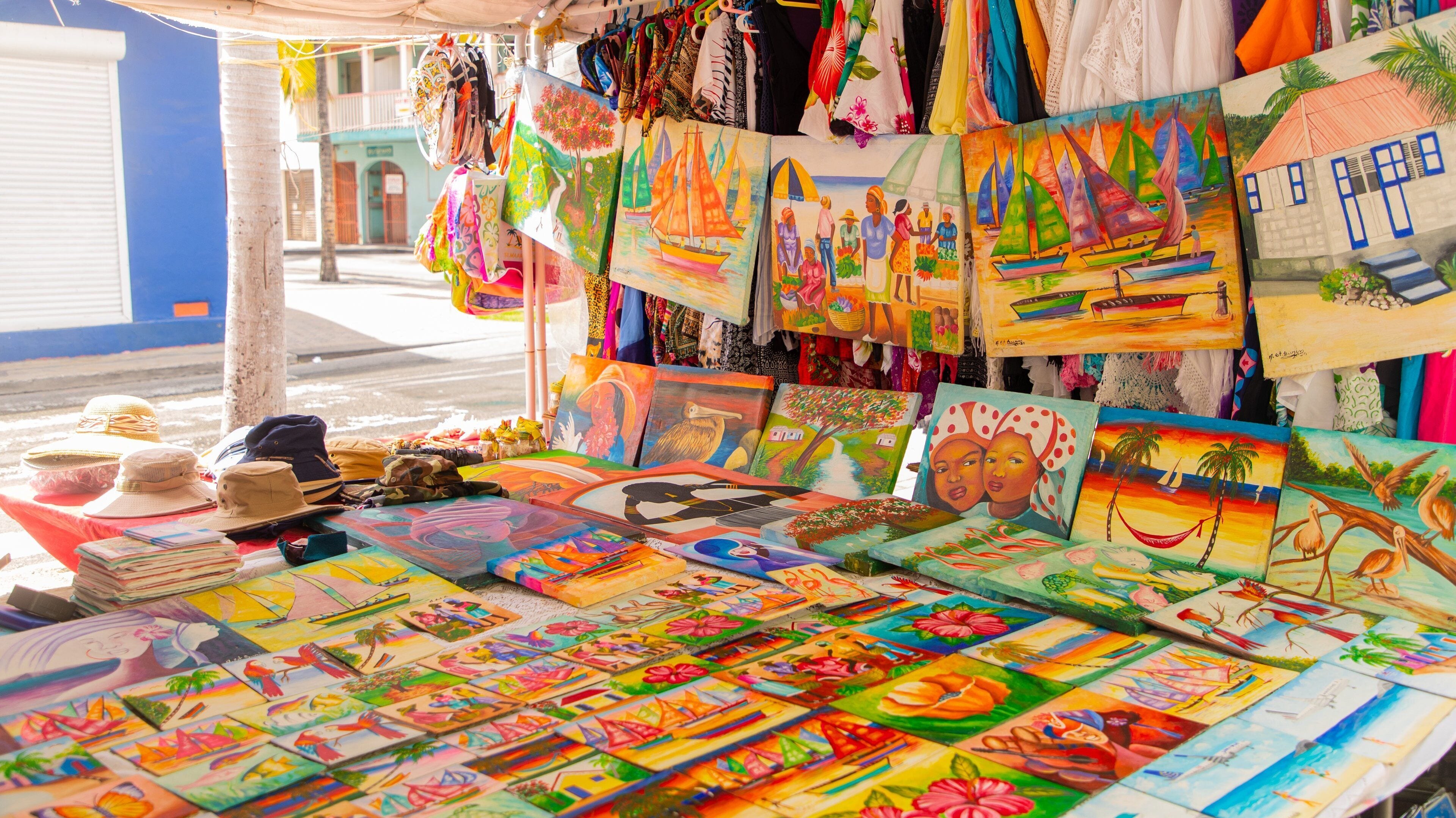 A vibrant market stall with colorful paintings, hats, and textiles.