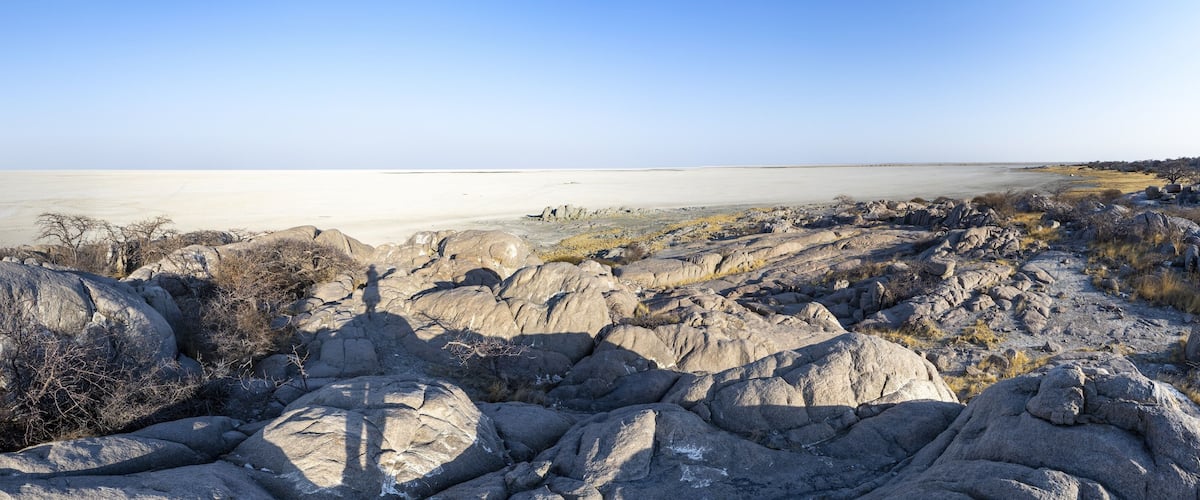 A rocky landscape with a flat, expansive body of water in the background.