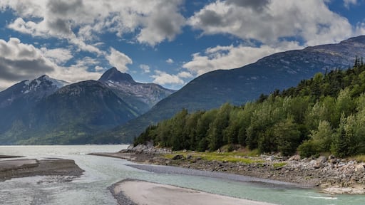 Panoramic shot of Yucatania point and shallow Skagway river in Skagway, Alaska. Mountains and cloudy blue sky as a background
