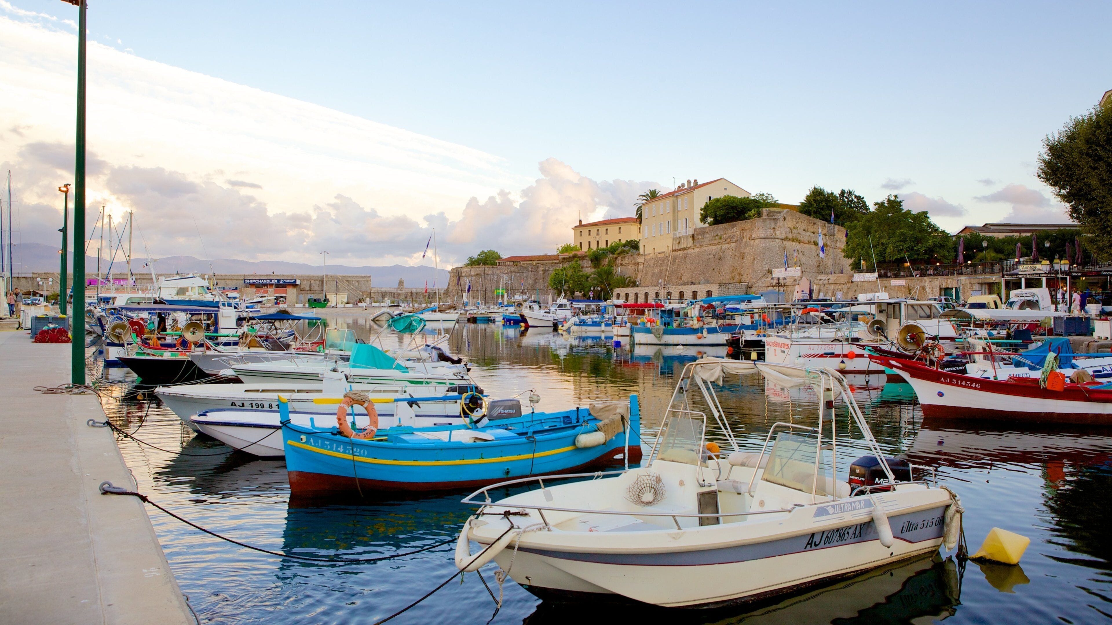 A harbor with numerous boats docked, a stone building, and a clear sky.