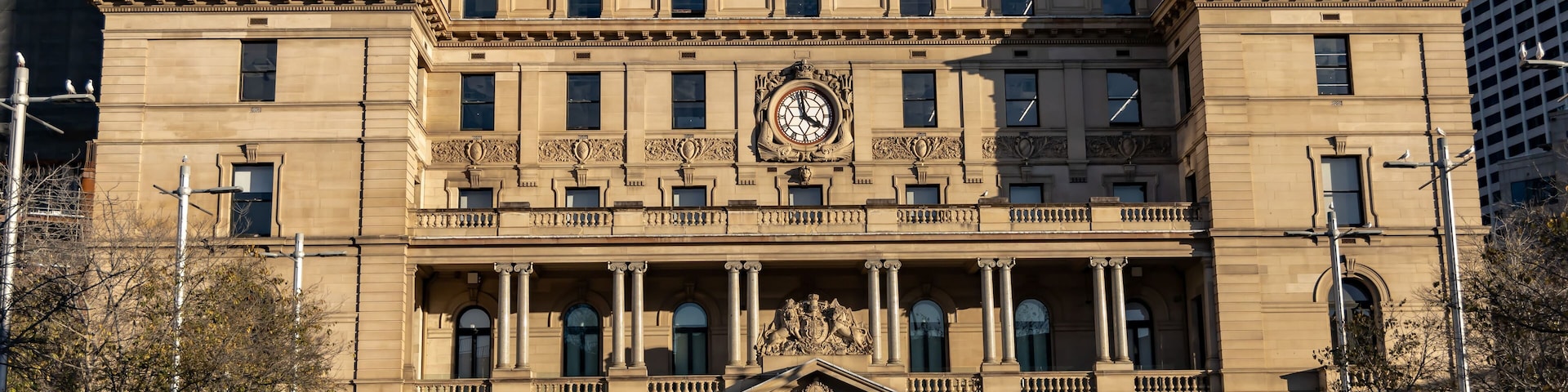 A historic building with a prominent clock tower, columns, and a flag.