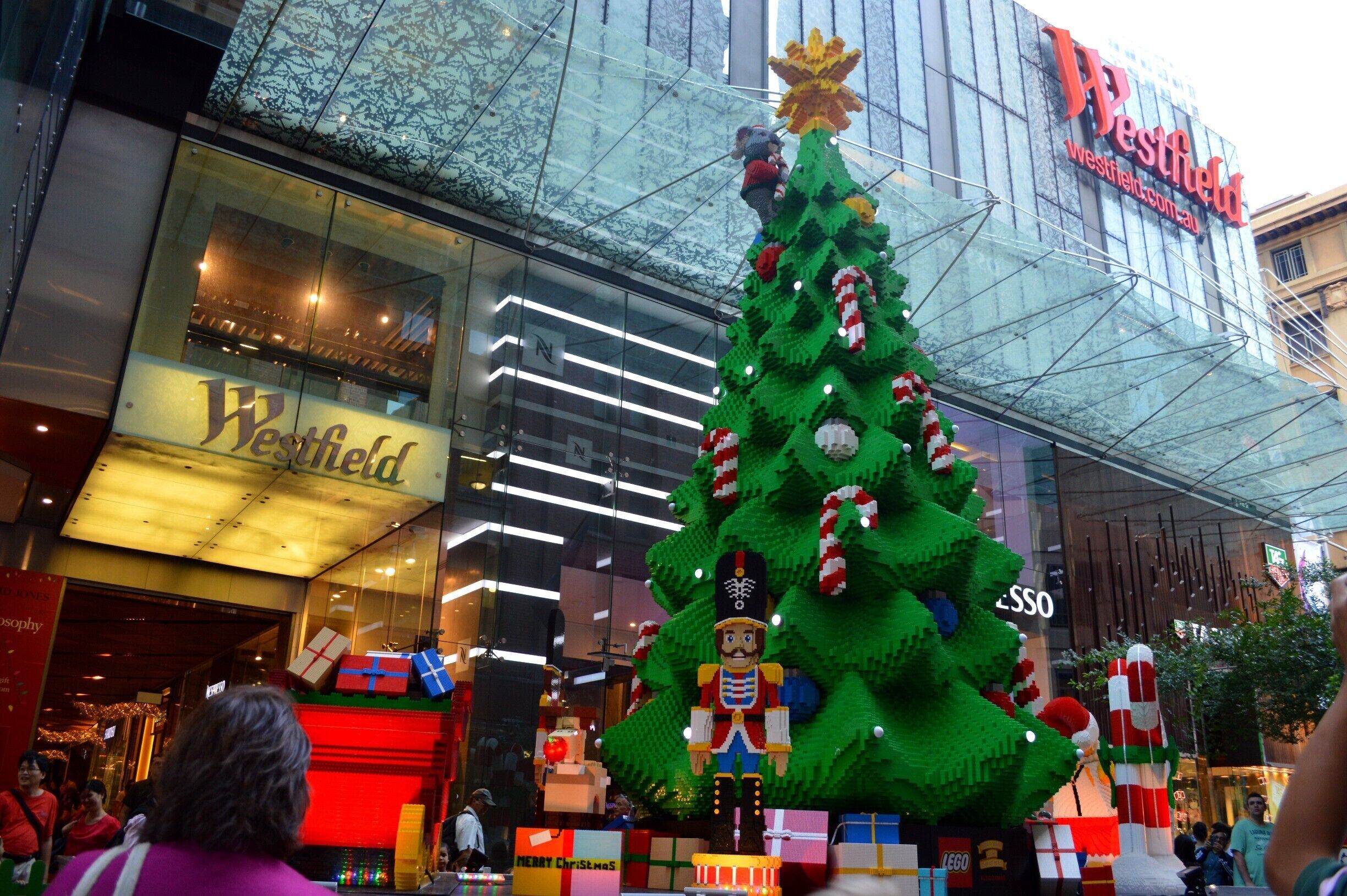 A LEGO Christmas tree with presents in front of a Westfield shopping mall.