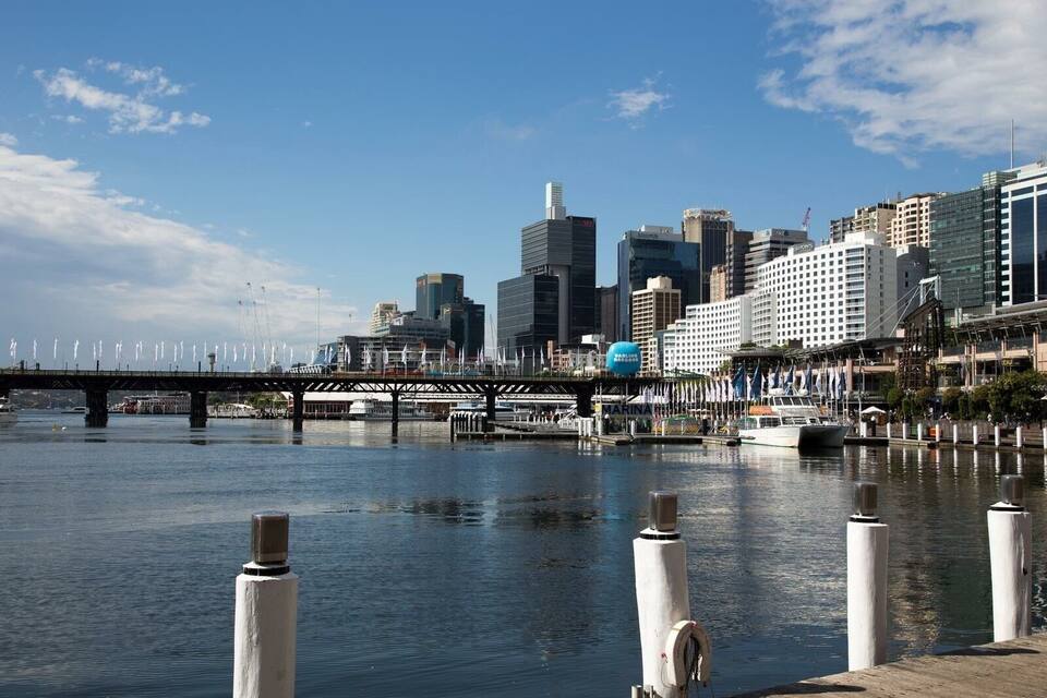 A waterfront cityscape with a bridge, modern buildings, and a marina.
