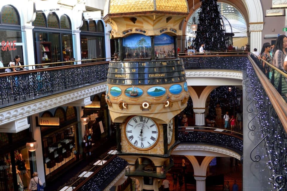 A shopping mall with a large clock tower, multiple levels, and a Christmas tree.