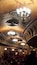 An ornate theater interior with multiple chandeliers and a crowd of people.