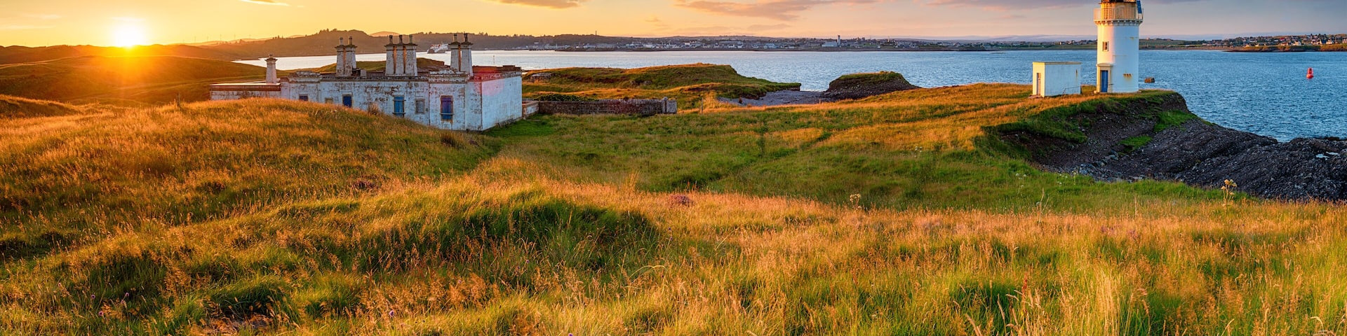 Panoramic view of sunset over the lighthouse and coastguard cottages at Arnish Point