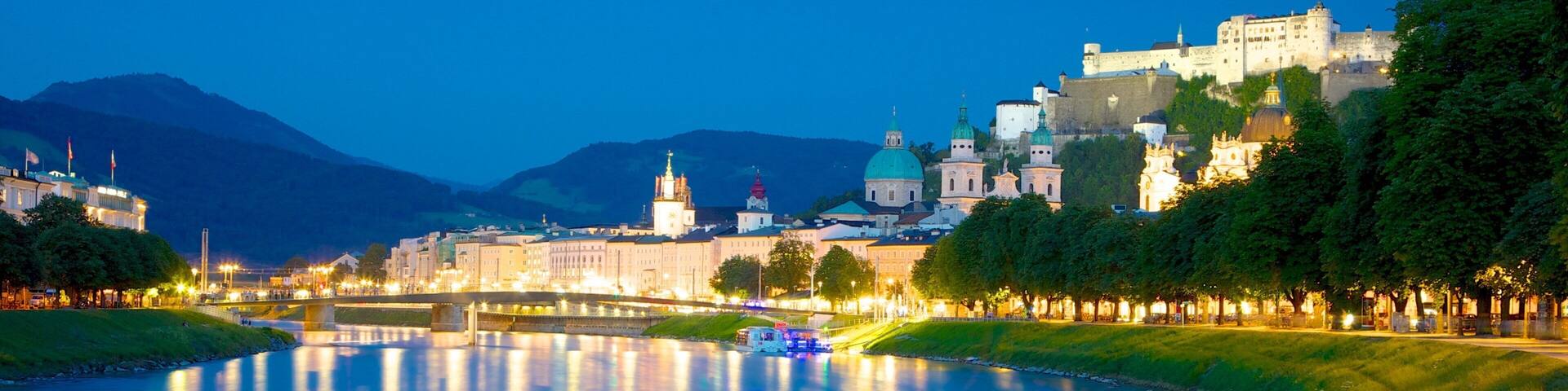 A river reflecting city lights, a castle on a hill, and a bridge in the foreground.